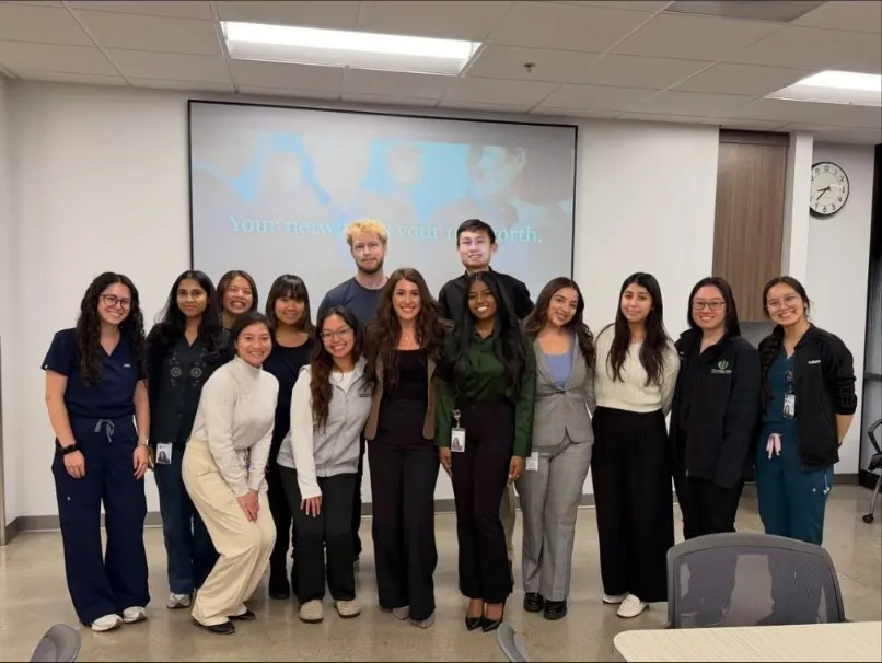 Joelle with a group of workshop participants in front of a screen reading Your network is your net worth