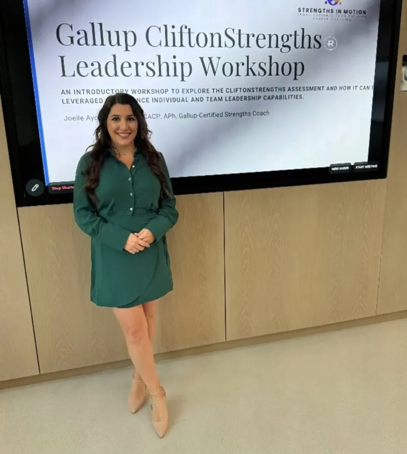 Joelle Ayoub standing in front of a screen reading Gallup CliftonStrengths Leadership Workshop